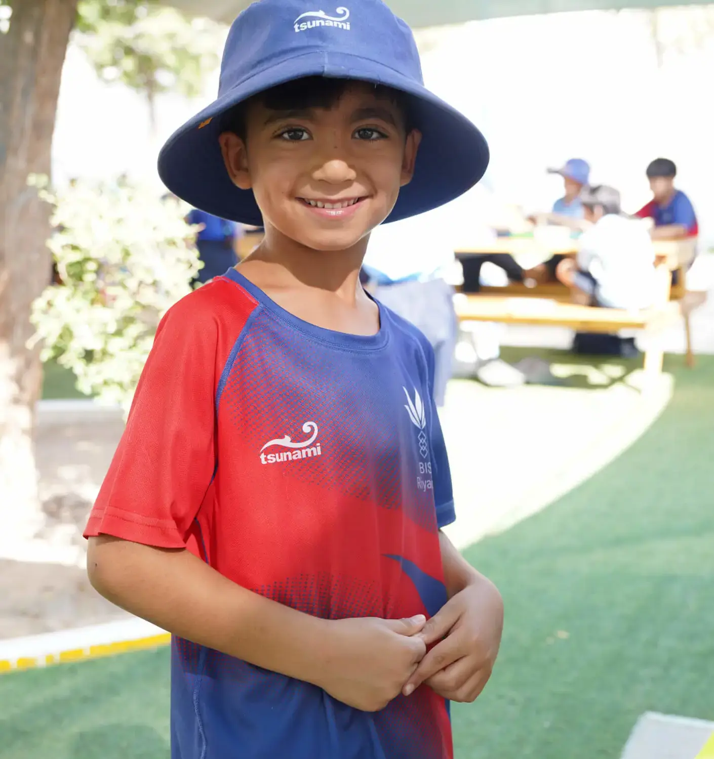 BISR Al Hamra student smiling and wearing a sun hat during a sports lesson.