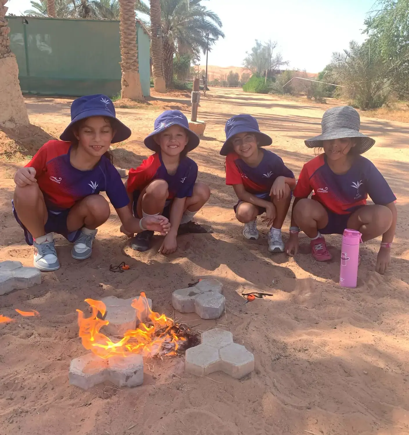BISR students sitting around a campfire during a field trip to a farm.
