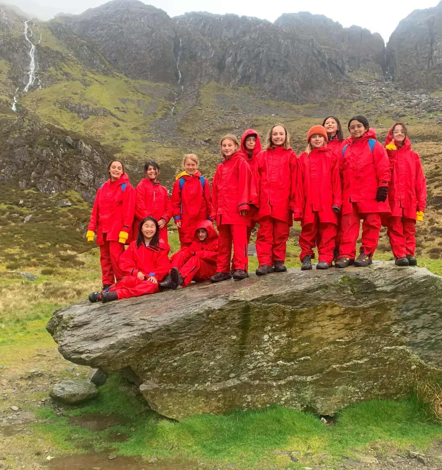 BISR students standing on a boulder during a field trip to Plas Menai.