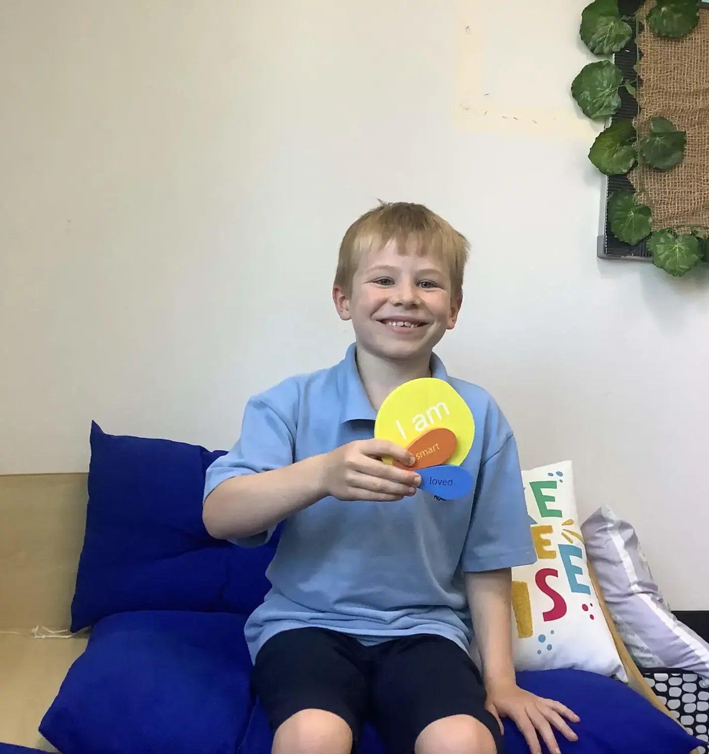 Junior student holding cards saying 'I am', 'smart', and 'loved'.